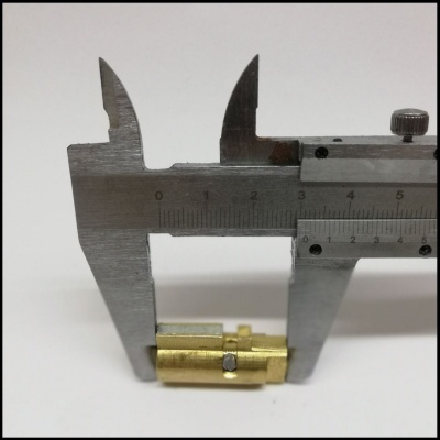 Paquímetro a medir objeto metálico dourado em fundo branco