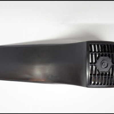 Peça plástica preta com grelha e parafuso central sobre fundo branco.