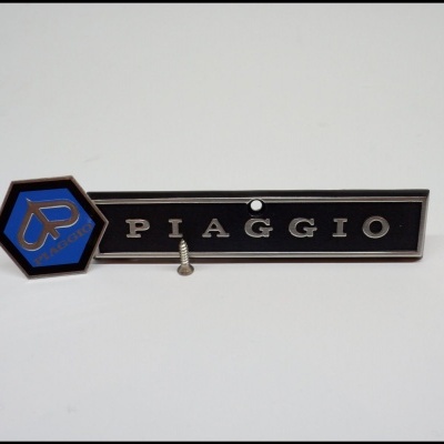 Emblema Piaggio preto e azul com parafuso em fundo branco