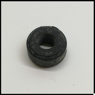 Peça circular preta com orifício central em superfície branca