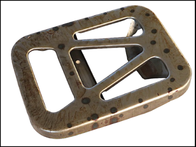 Peça metálica cinzenta com manchas escuras em fundo branco