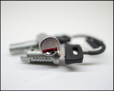 Fechadura de carro com duas chaves pretas num fundo branco