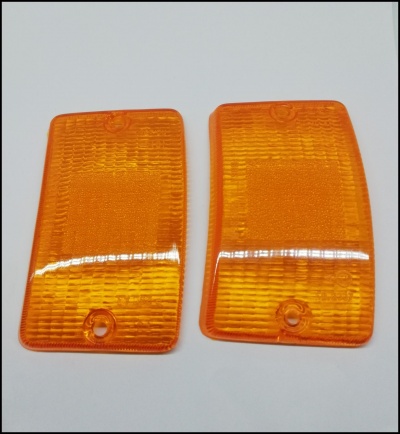 Duas tampas de vidro laranja translúcido com textura, sobre fundo branco