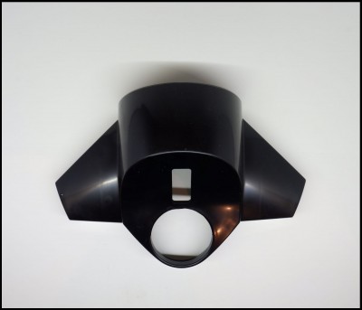 Peça plástica preta com orifícios em forma circular e retangular sobre fundo branco