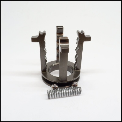 Peça metálica cinzenta com mola helicoidal e apoios verticais em fundo branco