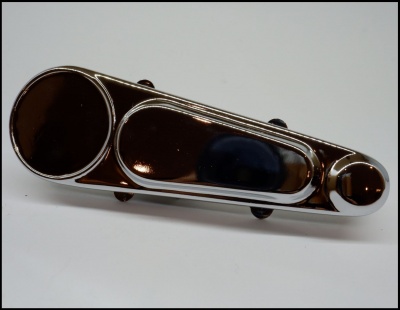 peça metálica cromada com círculos e seção oval sobre superfície branca