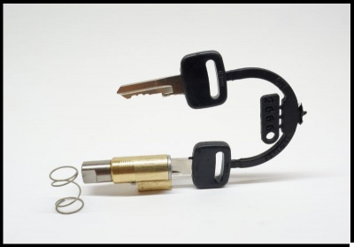 Fechadura cilíndrica dourada com chaves pretas e molas metálicas