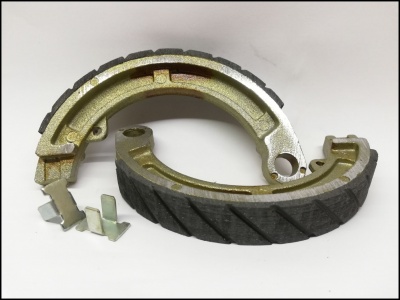 Lonas de travão de motocicleta com base metálica e revestimento preto com nervuras, peças metálicas pequenas ao lado