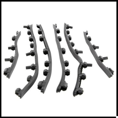 Peças plásticas curvas pretas com saliências cilíndricas sobre fundo branco