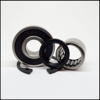 Rolamentos de esferas metálicos e peça preta sobre fundo branco