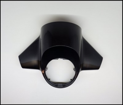 Peça preta em plástico com formato côncavo e duas extensões laterais sobre fundo branco