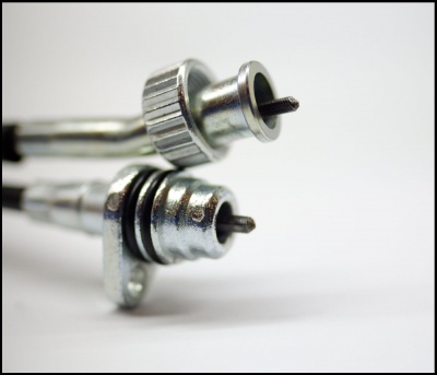 Duas válvulas metálicas cilíndricas com parafusos centrais e anéis de vedação em fundo branco