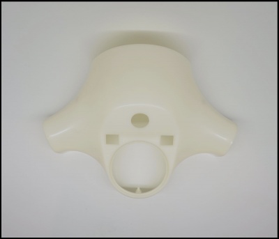 Peça plástica creme com orifícios circulares sobre fundo branco