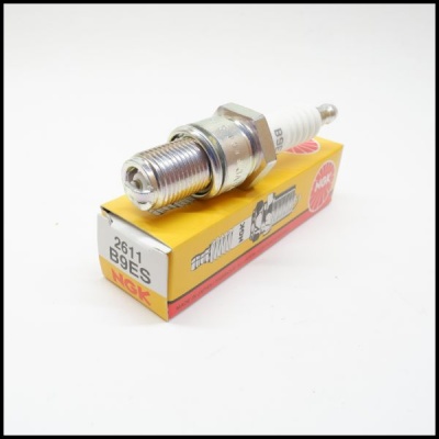 Vela de ignição B9ES sobre caixa amarela, vermelha e branca da marca NSK