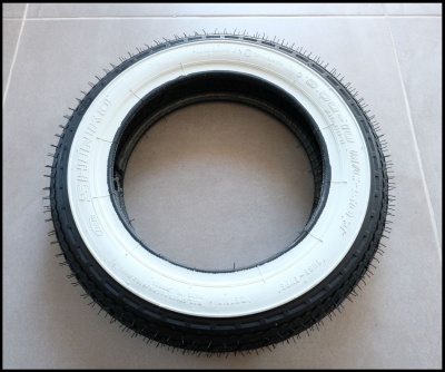 Pneu preto com faixa branca central sobre superfície clara