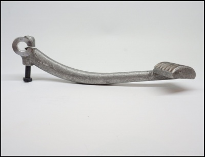 Pedal metálico cinzento com parafuso numa superfície branca