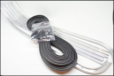 Tiras flexíveis transparentes, fita preta enrolada e saco com parafusos sobre superfície branca