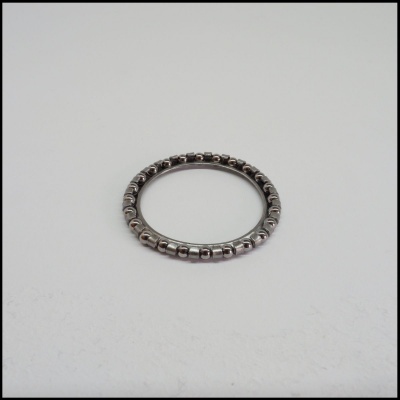 Anel metálico circular prateado com detalhes arredondados sobre fundo branco