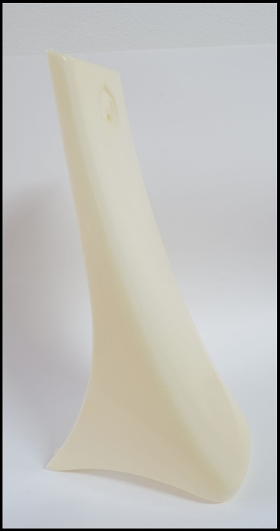 Peça alongada creme de plástico com contornos curvos sobre fundo branco