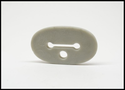 Botão oval cinzento com três orifícios sobre fundo branco