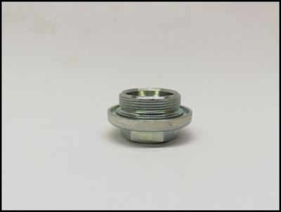 Peça metálica cilíndrica prateada com roscas, sobre superfície branca.