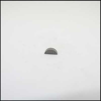 Peça metálica semicircular cinzenta sobre superfície branca