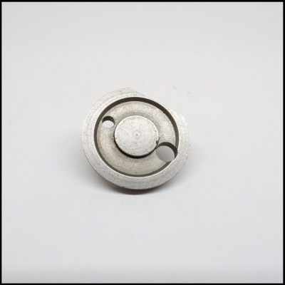 Peça metálica circular com duas aberturas e textura prateada