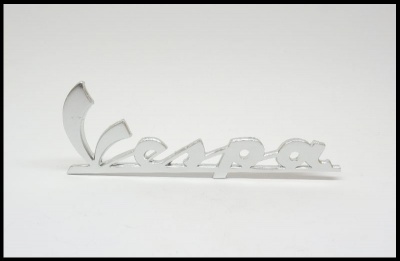Emblema metálico cromado com texto Vespa