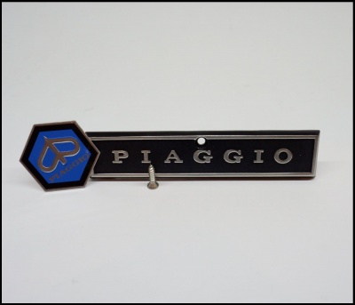 Emblema Piaggio preto e azul com parafuso em fundo branco