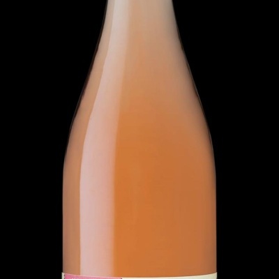 Garrafa de vinho rosé com rótulo creme e rosa sobre fundo negro