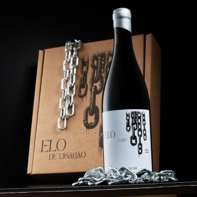 Garrafa de vinho tinto com etiqueta branca e caixa de cartão com design de correntes