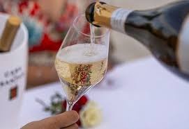 Taça de champanhe a ser servida com vinho espumante de garrafa dourada e preta