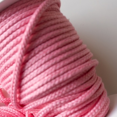 Carretel branco com linha rosa enrolada, textura torcida