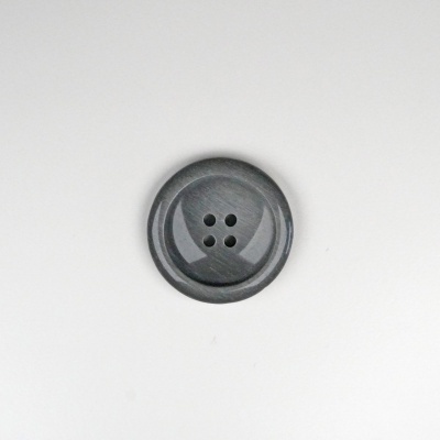 Botão redondo cinzento com quatro furos no centro sobre superfície branca