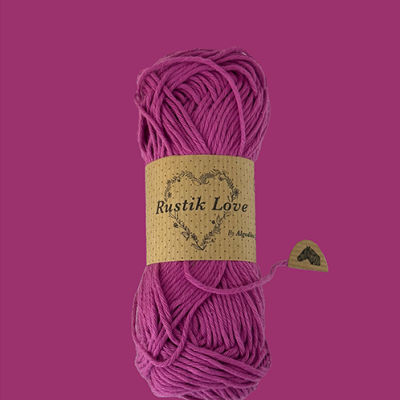 Novelo de lã roxa com etiqueta Rustik Love numa superfície roxa