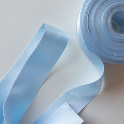 Rolo de fita azul clara com parte desenrolada sobre superfície branca