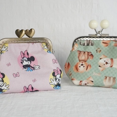 Duas carteiras pequenas em tecido com padrões distintos, uma rosa da Minnie Mouse e outra verde com gatos.