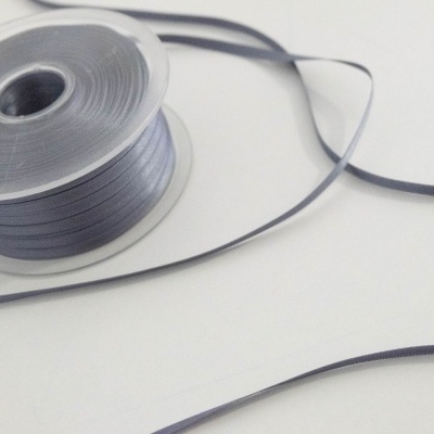 Carretel de fita adesiva cinzenta desenrolada sobre superfície branca