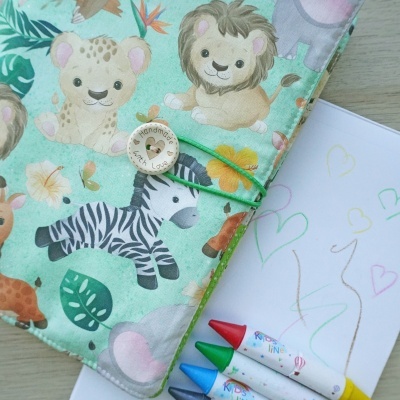 Capa de tecido com animais da selva e botão handmade com lápis de cera e desenho ao lado
