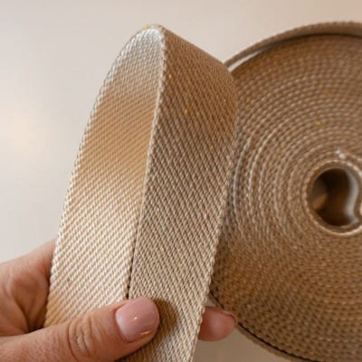 Rolo de fita têxtil bege com textura trançada segurado por mão