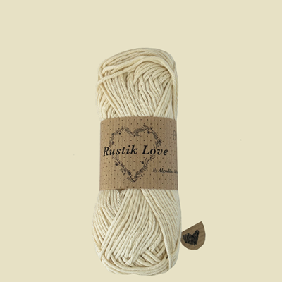 Novelo de fio macramê algodão cru com etiqueta Rustik Love em fundo bege