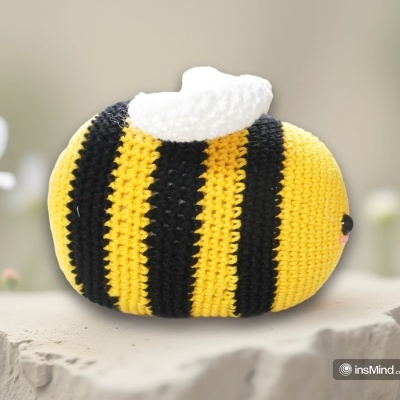 Pelúcia de crochê em forma de abelha com riscas amarelas e pretas e asas brancas
