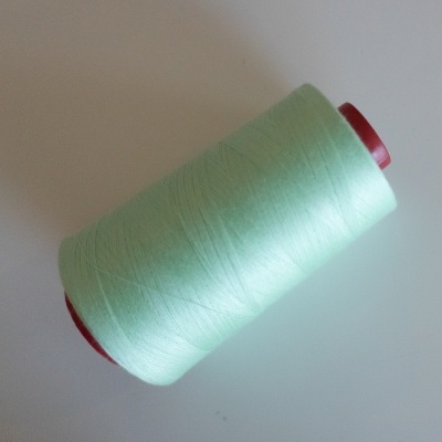 Rolo de linha verde claro num carretel vermelho sobre fundo branco