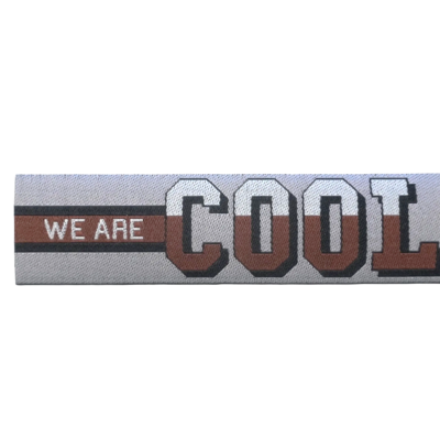 Faixa têxtil cinzenta com texto WE ARE COOL em relevo castanho e branco.