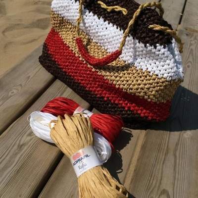 Mala de mão colorida em ráfia com carretéis de fio em madeira
