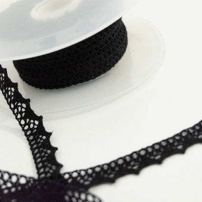 Rolo de fita preta em renda com padrão recortado sobre fundo branco
