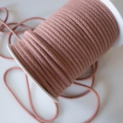 Carretel de cordão de tecido rosa velho em superfície branca