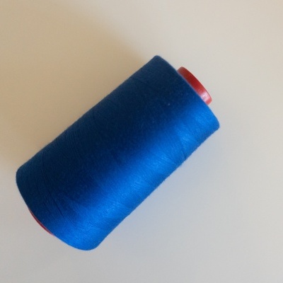 Rolo de linha azul escuro sobre superfície branca