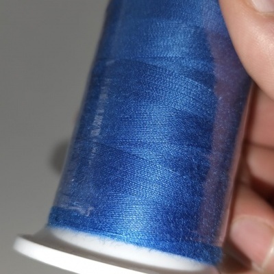 Carretel de linha azul segurado por uma mão