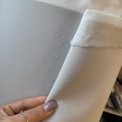 tecido branco texturizado segurado por mão feminina com unha pintada